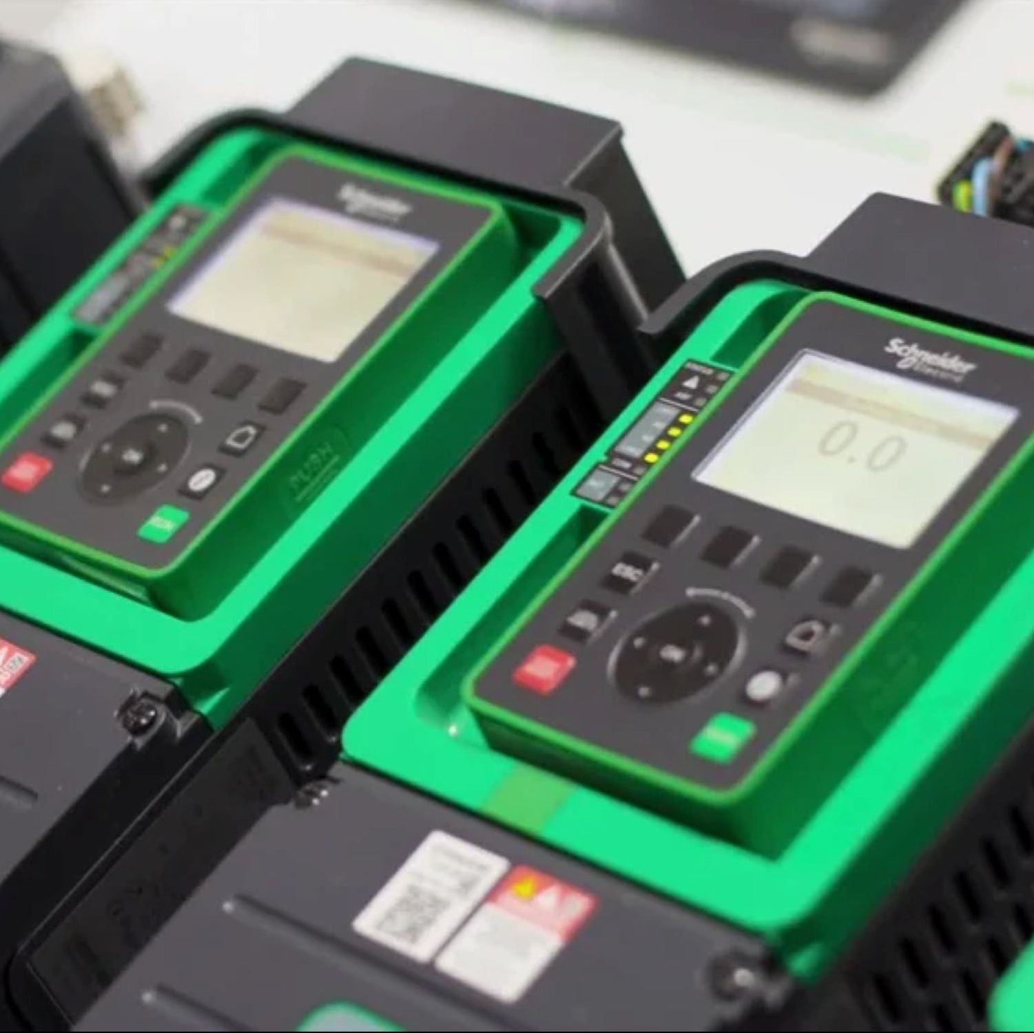 Row of frequency drives with digital displays and green covers on a blurred background